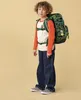 A young boy wearing a backpack and standing against a plain background. Produktbild-Vorschau