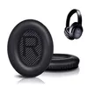 A close-up of black replacement ear pads for headphones, with a pair of black headphones in the background. Produktbild-Vorschau