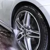 A car wheel being cleaned with a pressure washer. Produktbild-Vorschau