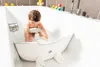 A baby is sitting in a bathtub using a white and gray bath insert. Produktbild-Vorschau