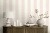 A decorative vignette on a wooden cabinet, featuring a lamp, candles, a bowl of pears, and a vase with branches, set against a striped pink and white wallpaper. Produktbild-Vorschau