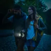 Two people hiking at dusk, one holding a lantern. Produktbild-Vorschau