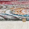 A close-up view of a rug with a detailed pattern, showing the texture and fibers. A coin is placed on the rug for scale. Podgląd zdjęcia produktu
