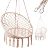 A beige macrame hanging chair with tassels is shown against a white background. A smaller, similar chair is visible in the background, and a close-up of the hanging ropes and metal rings is in the upper right corner. Podgląd zdjęcia produktu