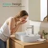 A woman is washing her face at a modern bathroom sink. Voir les images du produit