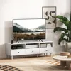 A modern living room scene featuring a white TV stand with a television, decorative items, and a large plant. Produktbild-Vorschau