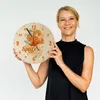 A woman is holding a round clock with a cocktail design. Produktbild-Vorschau
