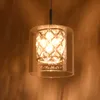 A close-up shot of a modern pendant light with a glass shade and crystal accents, hanging against a brown wall. Produktbild-Vorschau