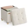A storage ottoman with its lid open, revealing folded blankets inside. The ottoman is on a white background. Produktbild-Vorschau