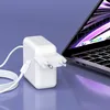 A white USB-C charger and cable are placed next to an open laptop. Podgląd zdjęcia produktu