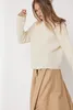 A woman wearing a cream-colored sweater and a beige skirt against a white background. Produktbild-Vorschau
