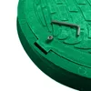 A close-up view of a green manhole cover with a hex key and a screw. Podgląd zdjęcia produktu