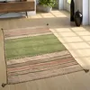 A rug is placed on a wooden floor in a room with sunlight streaming in.