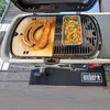 A grill with sausages and vegetables being cooked on it. Produktbild-Vorschau