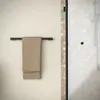 A towel rack with a tan towel hanging on it, mounted on a cream-colored wall next to a shower stall. Produktbild-Vorschau