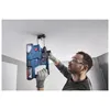 A man is using a cordless hammer drill to drill into a ceiling. Produktbild-Vorschau