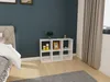A white cube shelf unit with decorative items on top, placed in a bedroom next to a bed and a window with curtains. Produktbild-Vorschau