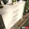 A close-up view of a light wood dresser with four silver handles, set against a floor with visible wood grain. Produktbild-Vorschau