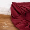 A close-up of a burgundy fitted sheet draped over a white mattress, with a wooden floor in the foreground. Produktbild-Vorschau