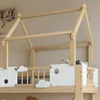 Close-up view of a wooden children's bunk bed with a house-shaped frame and white panels decorated with cloud cutouts. Produktbild-Vorschau