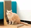 A cat sits on a scratching post next to a blue couch. Podgląd zdjęcia produktu