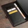 A close-up view of a black leather wallet with red stitching, holding credit cards and a banknote. Anteprima dell’immagine prodotto