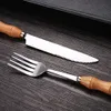 A close-up shot of a fork and knife with wooden handles, resting on a dark wooden surface. Voir les images du produit