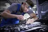 A mechanic is working on a car engine with a headlamp. Náhled obrázku produktu