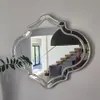 A decorative mirror hanging on a wall, reflecting a staircase and a person holding a phone. Produktbild-Vorschau