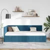 A blue velvet daybed with a white mattress and two pillows is shown in a room with shelves on the wall and a floor lamp. Produktbild-Vorschau