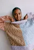 A woman is shown wearing a colorful, patchwork sweater. Produktbild-Vorschau