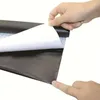 A hand peeling the backing off a black adhesive sheet. Produktbild-Vorschau