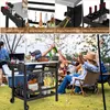 A group of people are enjoying a barbecue, with a grill cart prominently featured. Produktbild-Vorschau
