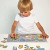 A young boy is playing with a magnetic puzzle of a city street with cars. Produktbild-Vorschau