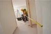 A construction worker is measuring a doorway with a tape measure in a room under renovation. Voir les images du produit