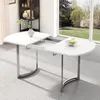 A white dining table with silver metal legs is shown in a well-lit room with a large window overlooking a garden. Anteprima dell’immagine prodotto