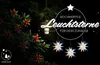 A dark outdoor scene at night, featuring a decorated tree branch with red and yellow star-shaped flowers, a hanging lantern, and three white paper stars hanging in the foreground. Text overlays promote "Hochwertige Leuchtsterne für dein Zuhause" (High-qual Produktbild-Vorschau