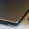 A close-up view of a laptop's side port with a power adapter plug about to be inserted. Voir les images du produit