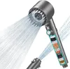 A close-up, studio shot of a modern shower head with water spraying from it, against a white background. A cutaway view reveals the filtering layers inside the handle. Produktbild-Vorschau