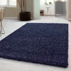 A dark blue shaggy rug is laid out on a light-colored floor in a room with furniture and plants. Anteprima dell’immagine prodotto