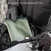 A person wearing gloves and a jacket is placing a green hydration reservoir into a backpack. Produktbild-Vorschau