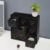 A black wooden organizer with nine drawers sits on a white surface next to a mirror and a potted plant. Podgląd zdjęcia produktu