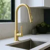 A gold kitchen faucet is shown in a modern kitchen setting, with a sink and countertop visible. Produktbild-Vorschau