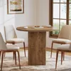 A round dining table with chairs in a room with a window and artwork. Produktbild-Vorschau