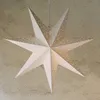 A white paper star lantern with many small perforations, hanging from a cord against a textured wall. Podgląd zdjęcia produktu