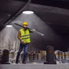 A construction worker carrying a metal beam in a warehouse. Produktbild-Vorschau