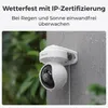 A white Reolink security camera mounted on a gray wall, with rain falling on it and green foliage in the background. Produktbild-Vorschau