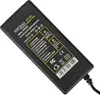 A black AC/DC adapter with a yellow label showing product information and safety warnings. Produktbild-Vorschau