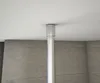 A close-up view of a shower enclosure pole attached to a ceiling, with a tiled wall in the background. Produktbild-Vorschau