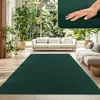 A living room scene with a large green rug, sofas, and plants. Produktbild-Vorschau